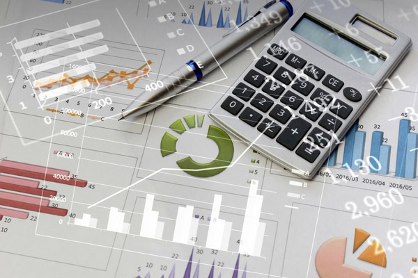 A calculator and pen rest on printed financial charts displaying graphs, numbers, and data visualizations—tools that great CFOs rely on for insightful financial analysis.